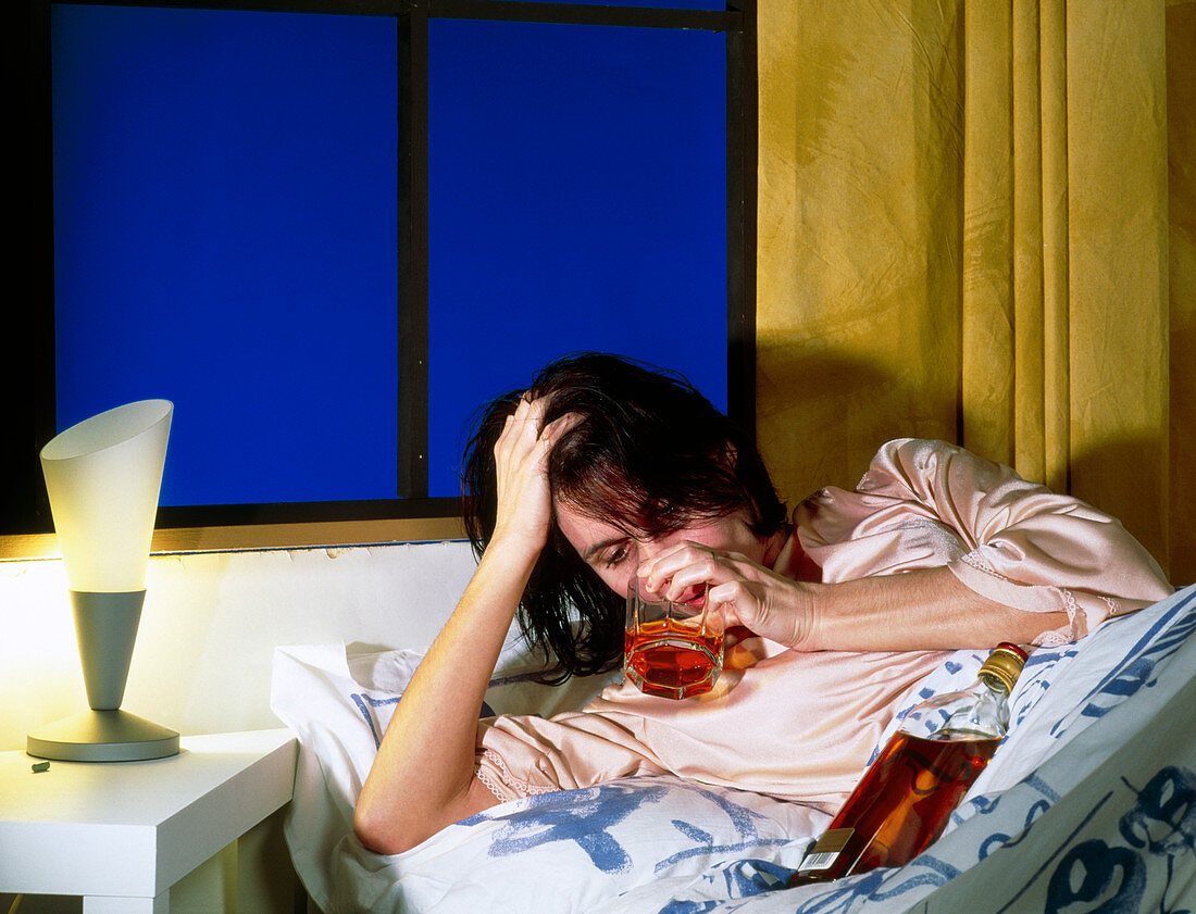 Woman drinking alcohol in bed