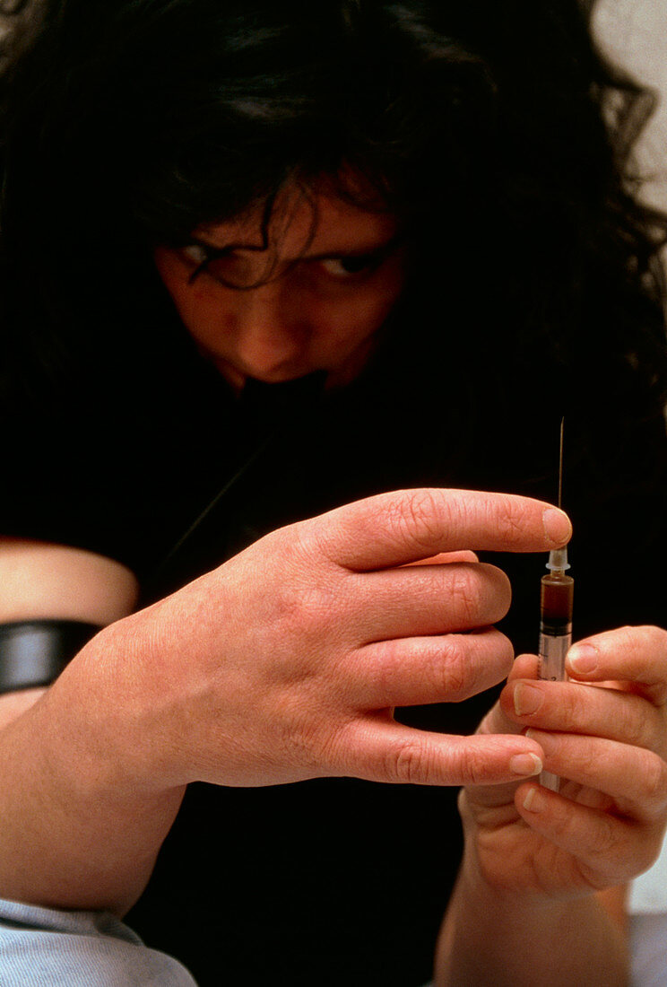 Heroin user prepares a syringe for injection