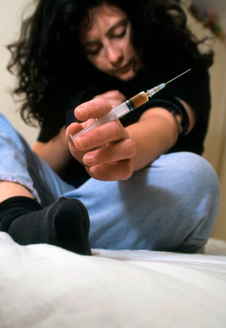 Heroin user about to inject the drug into her arm