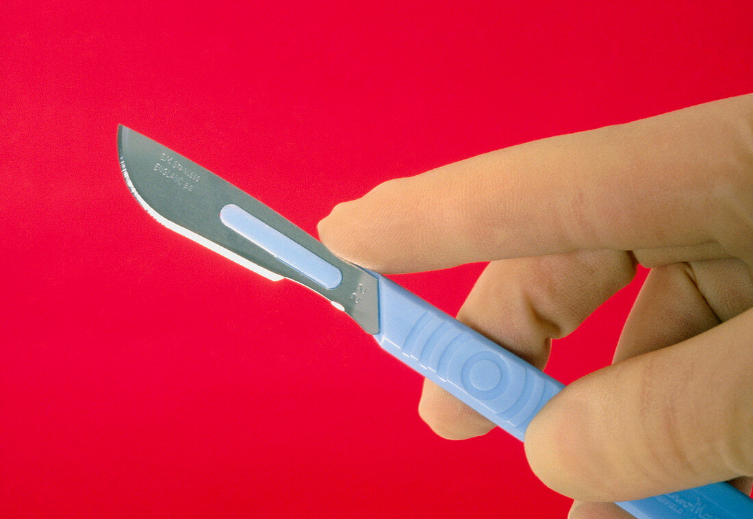 Gloved hand holding a disposable medical scalpel