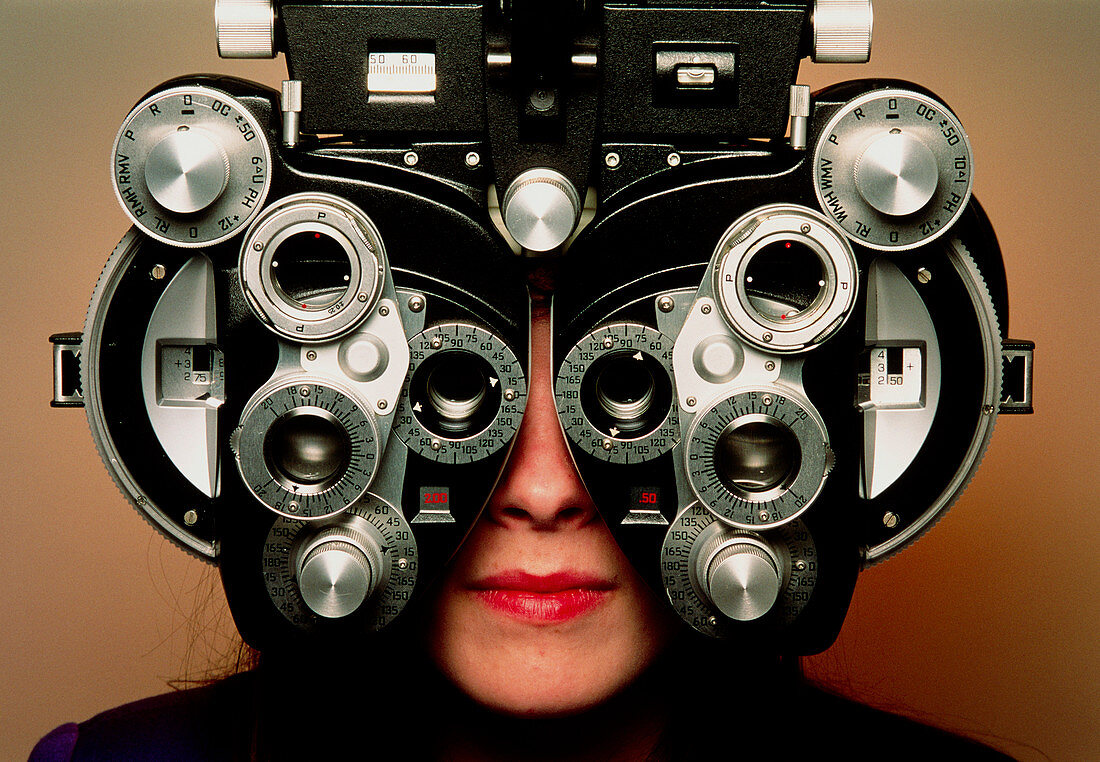 Eye examination: woman looks through a refractor