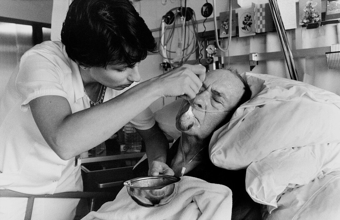 Elderly man being spoon-fed by nurse