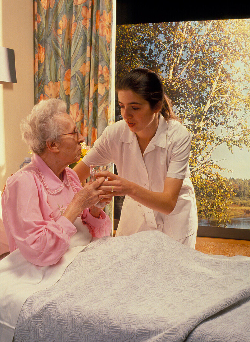 Nurse giving elderly woman glass of water