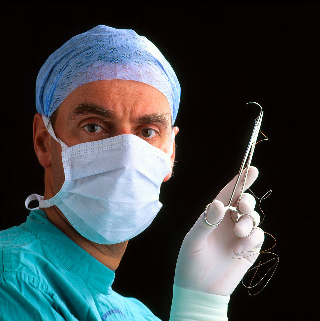 Close-up of masked surgeon holding suture