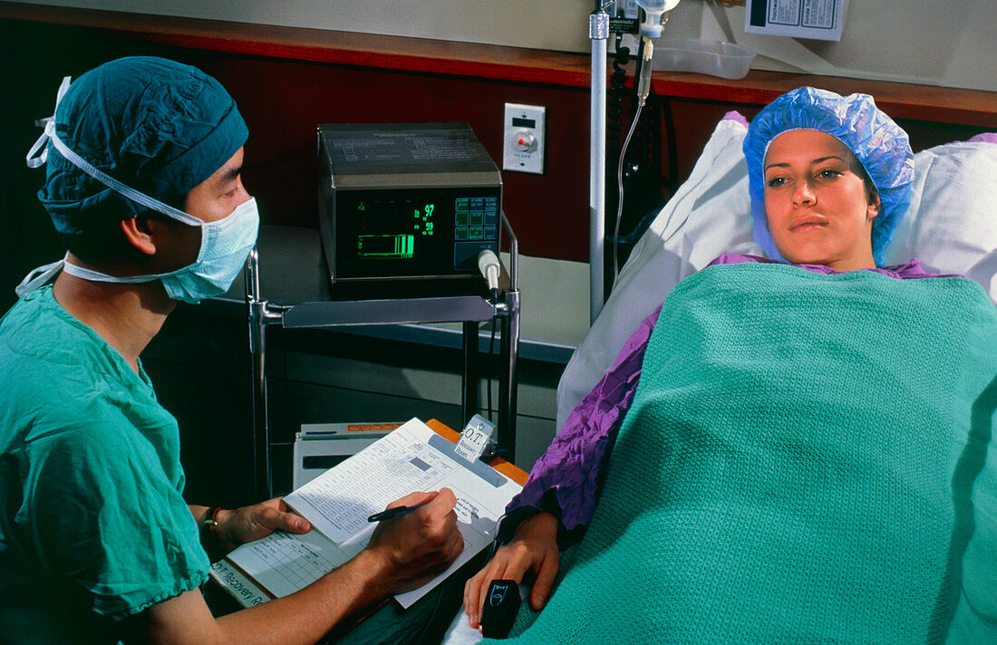 Surgeon monitors female patient after surgery