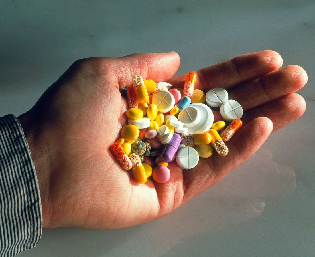 Hand holding assorted pills,tablets & capsules