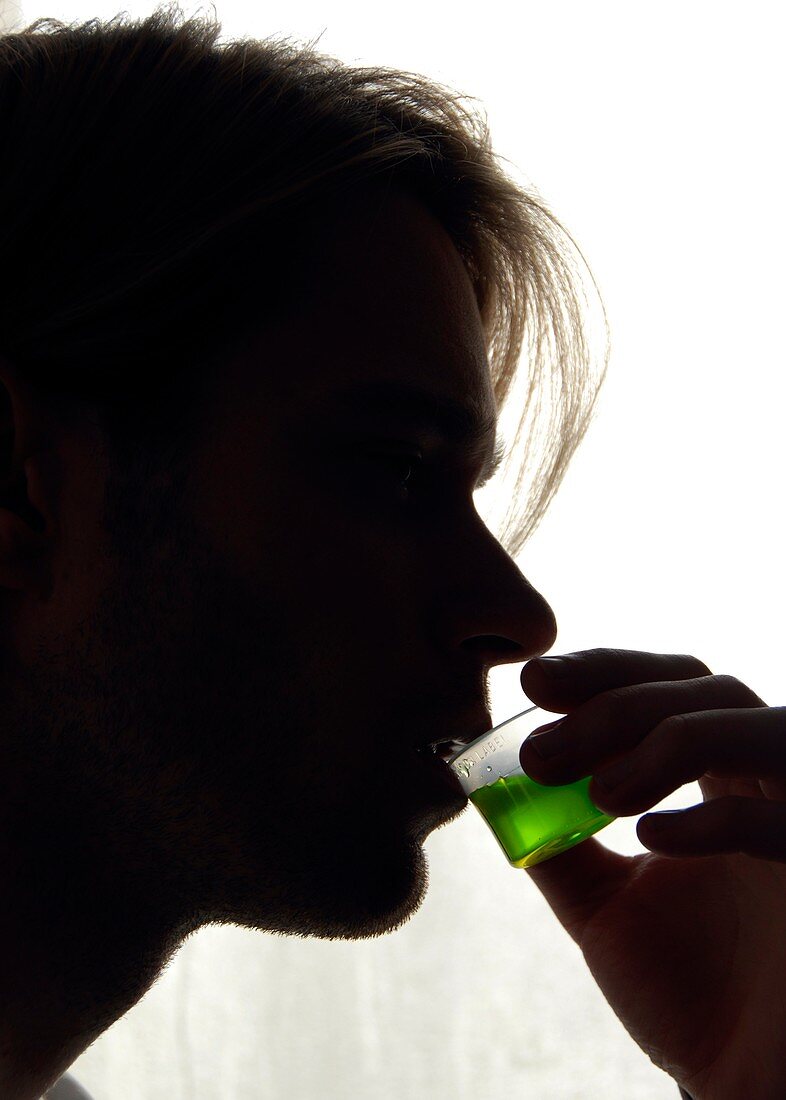 Drug addict drinking a measure of methadone