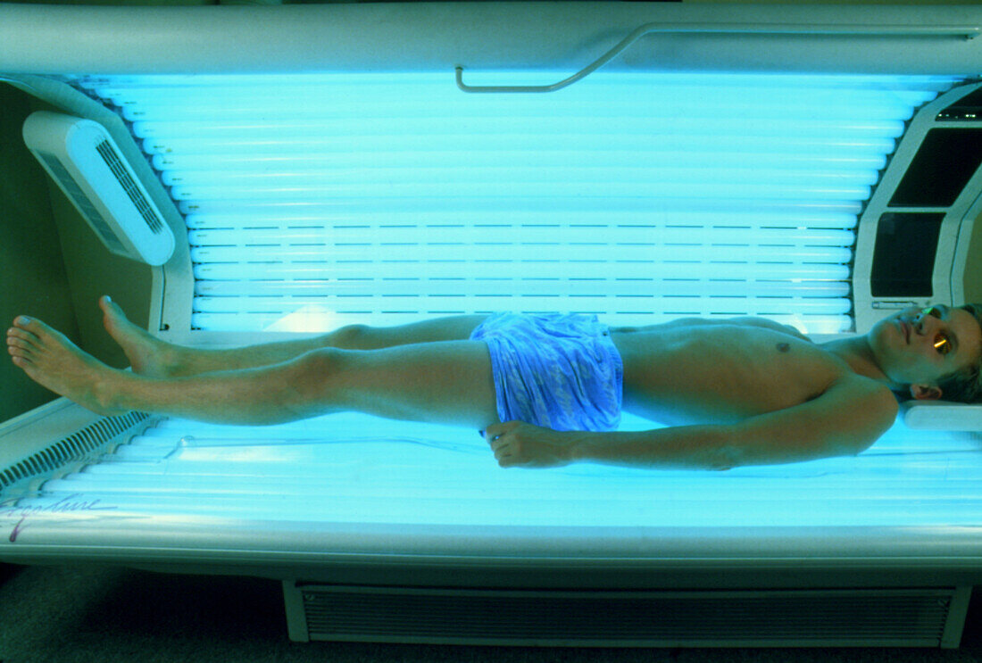 Teenage boy using an ultraviolet light sunbed