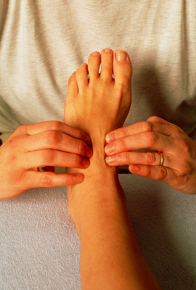 Hands of a reflexologist massaging a woman's foot