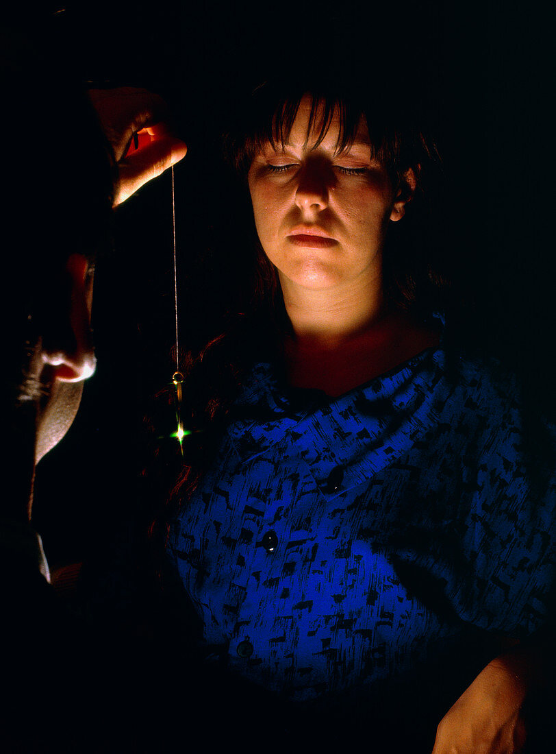 Woman under hypnosis via use of pendulum