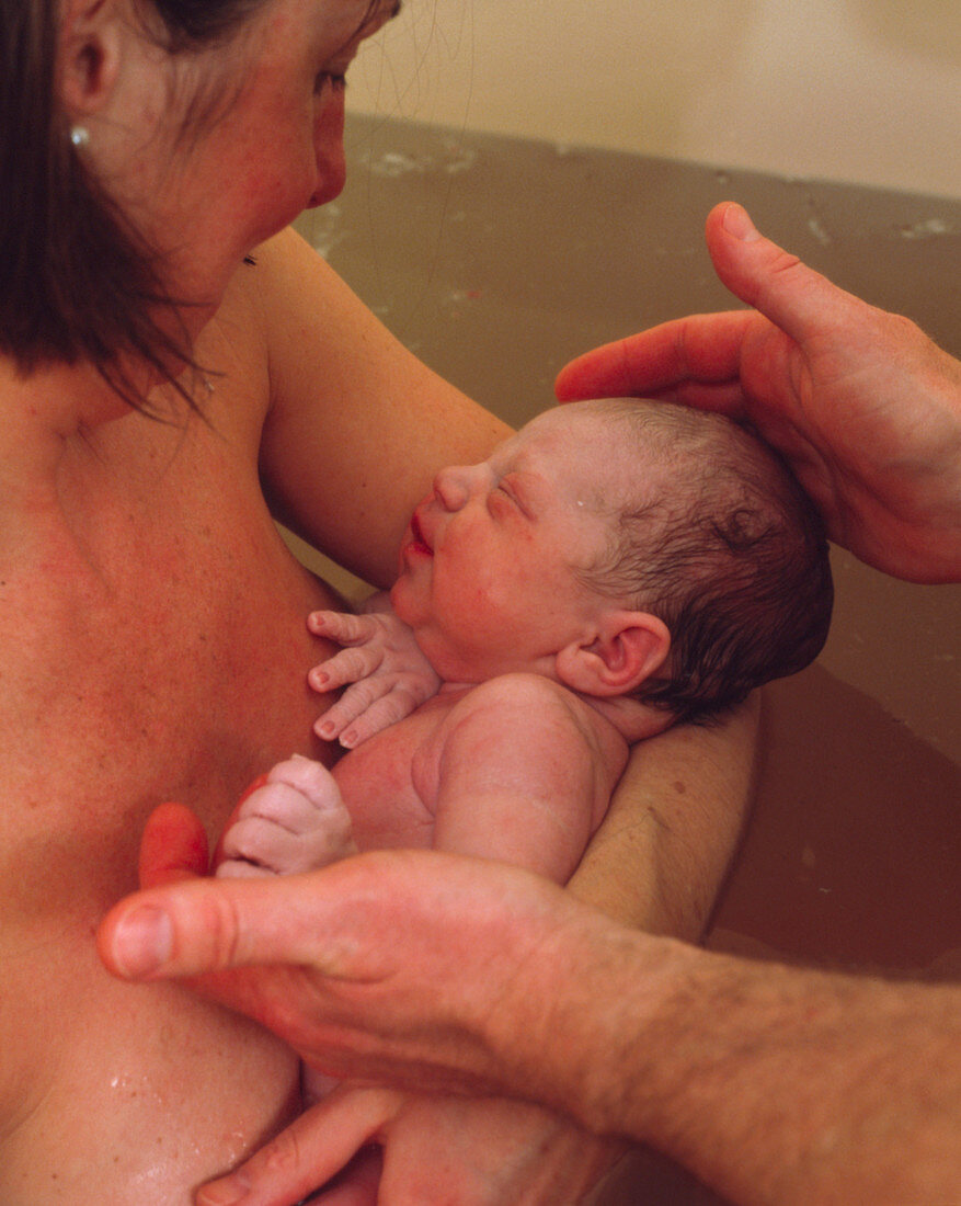 Water birth: mother holds her newborn baby