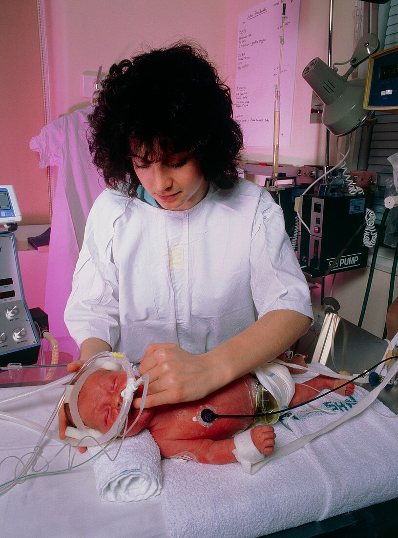 Nurse tending a newborn baby in intensive care