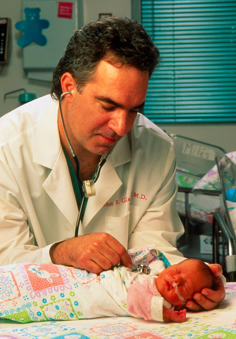 Newborn baby on oxygen is examined by a doctor