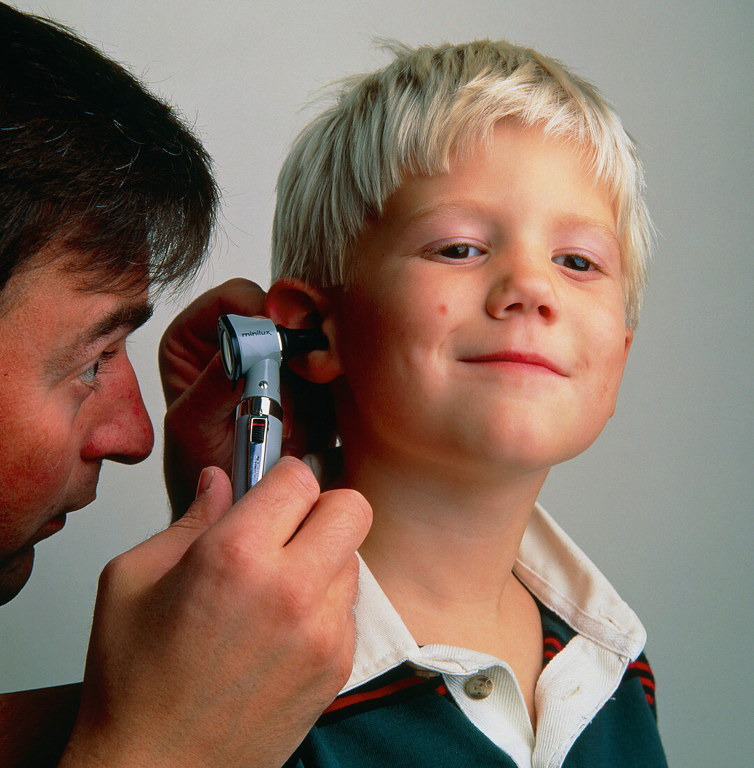 Doctor examines ear of young boy using an otoscope