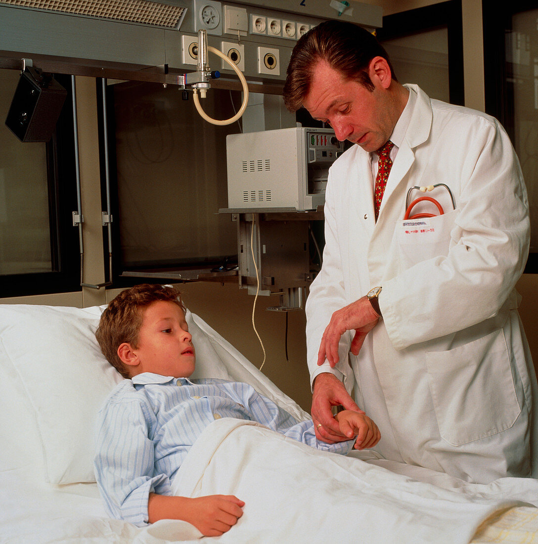 Doctor measures the pulse of a boy in hospital