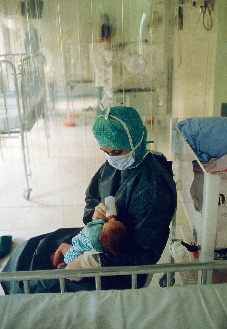 Nurse feeds immunodeficient baby in sterile room