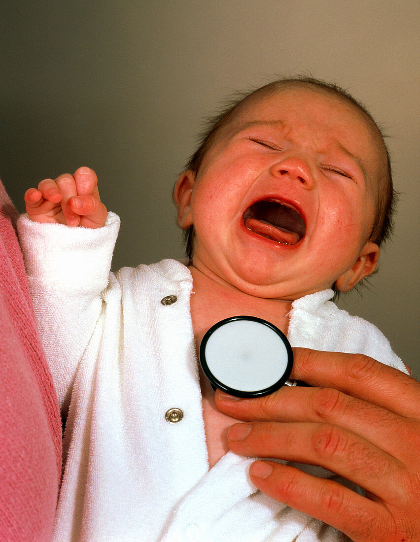 Doctor examining crying baby girl