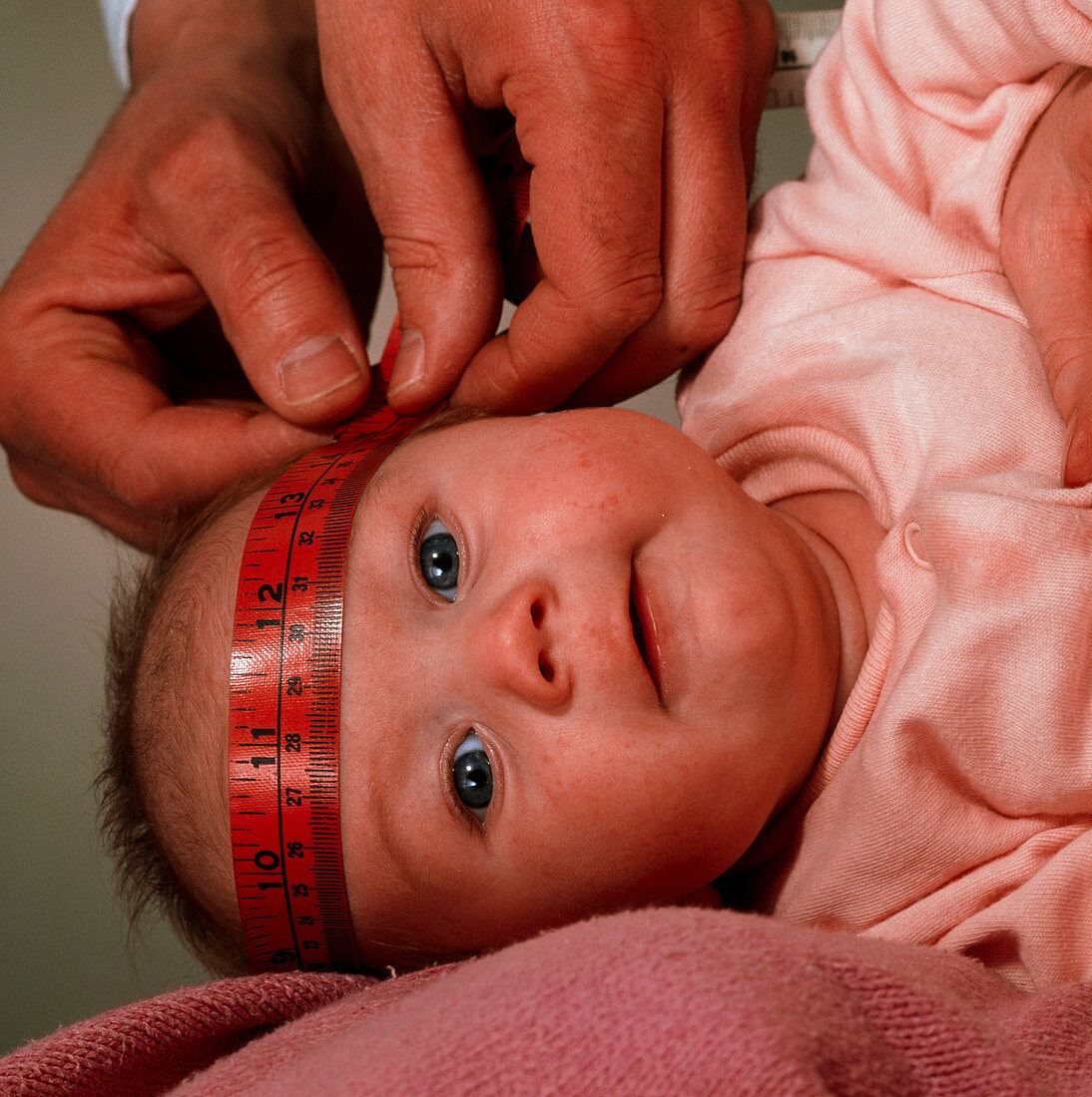 Doctor's hands measuring with tape a baby's head