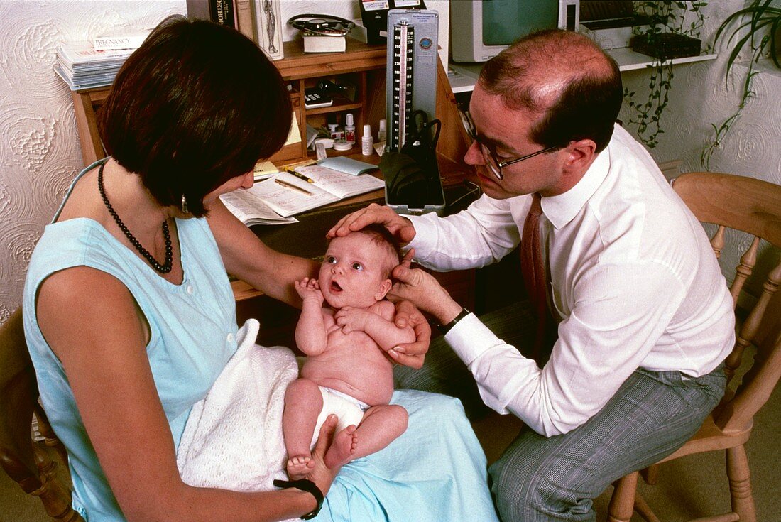 GP examining baby's head during postnatal check-up