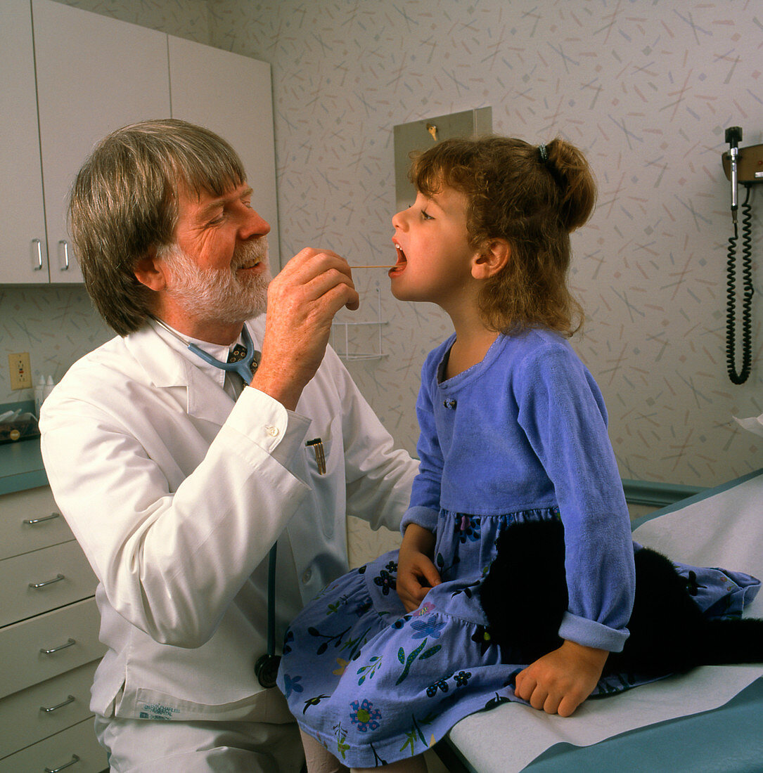 General practice doctor examines a girl's throat