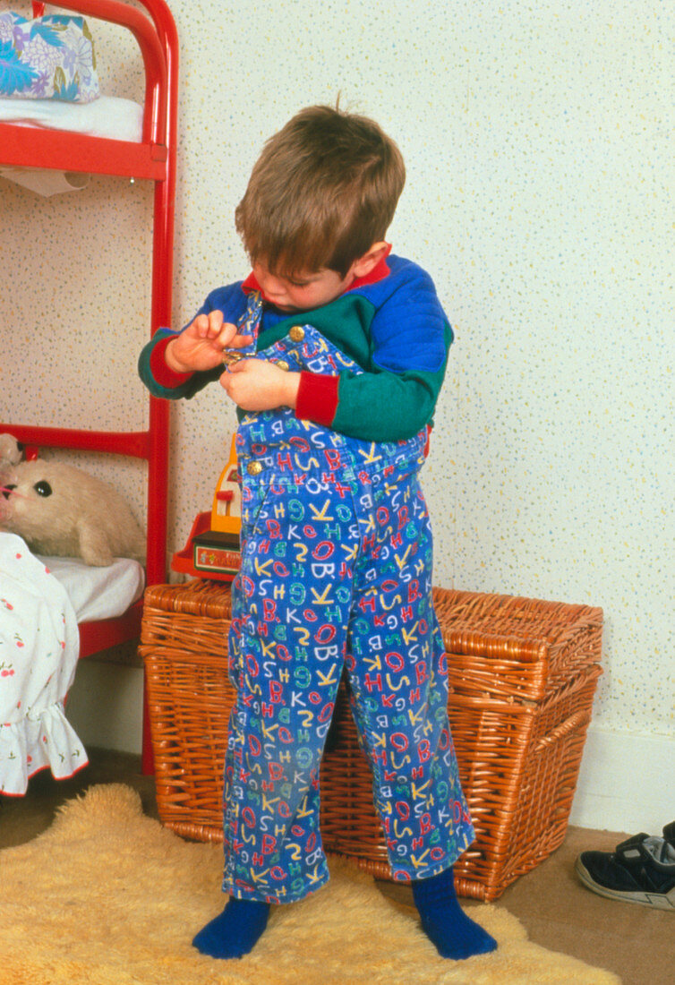 Young child adjusting his dungarees