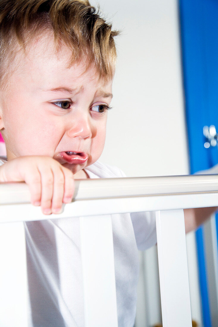 Upset toddler in his cot