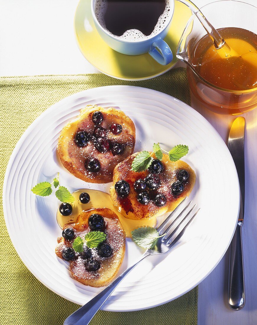 Blueberry pancakes on plate; cup of coffee, honey
