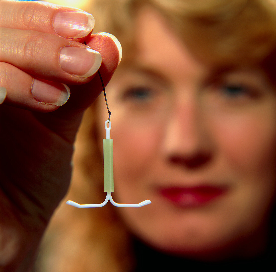 Woman holding intrauterine contraceptive device