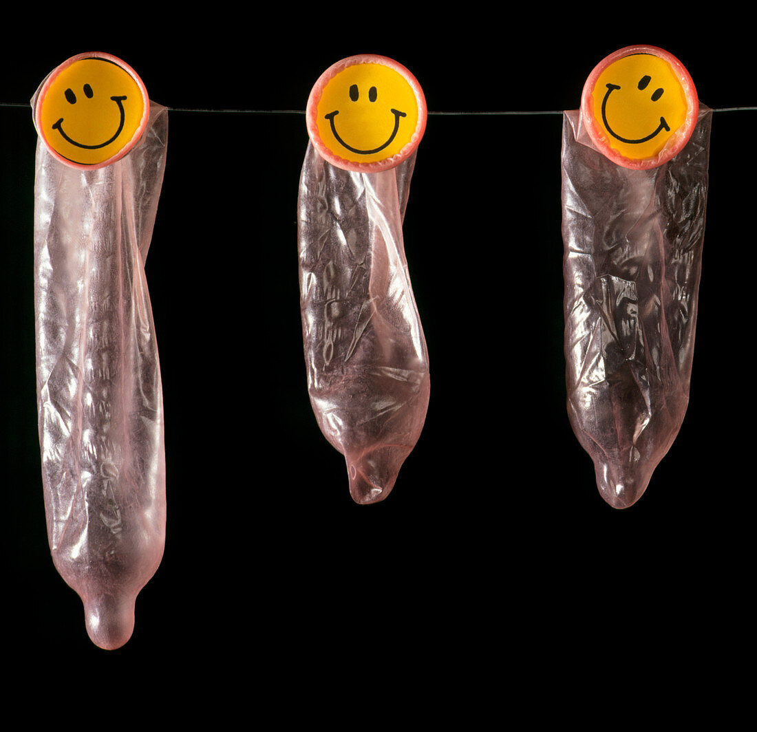Three condoms with smiley faces on washing line