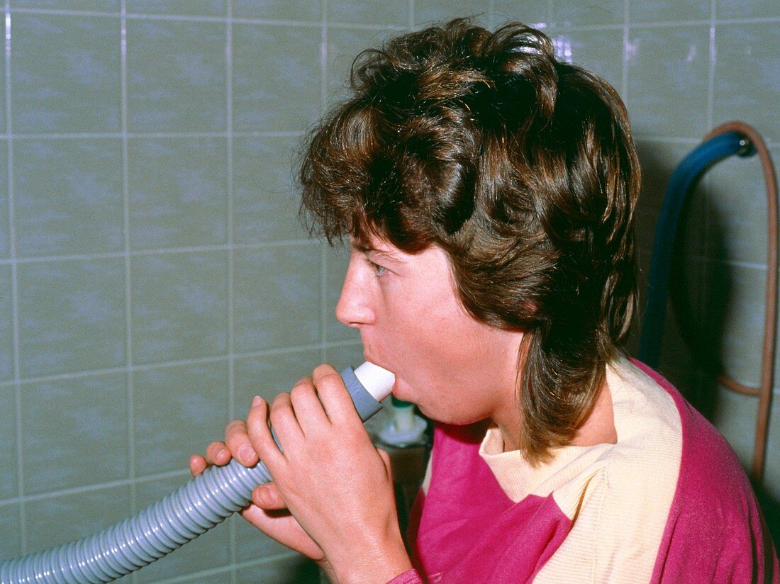 Woman using peak flow meter,asthma assessment