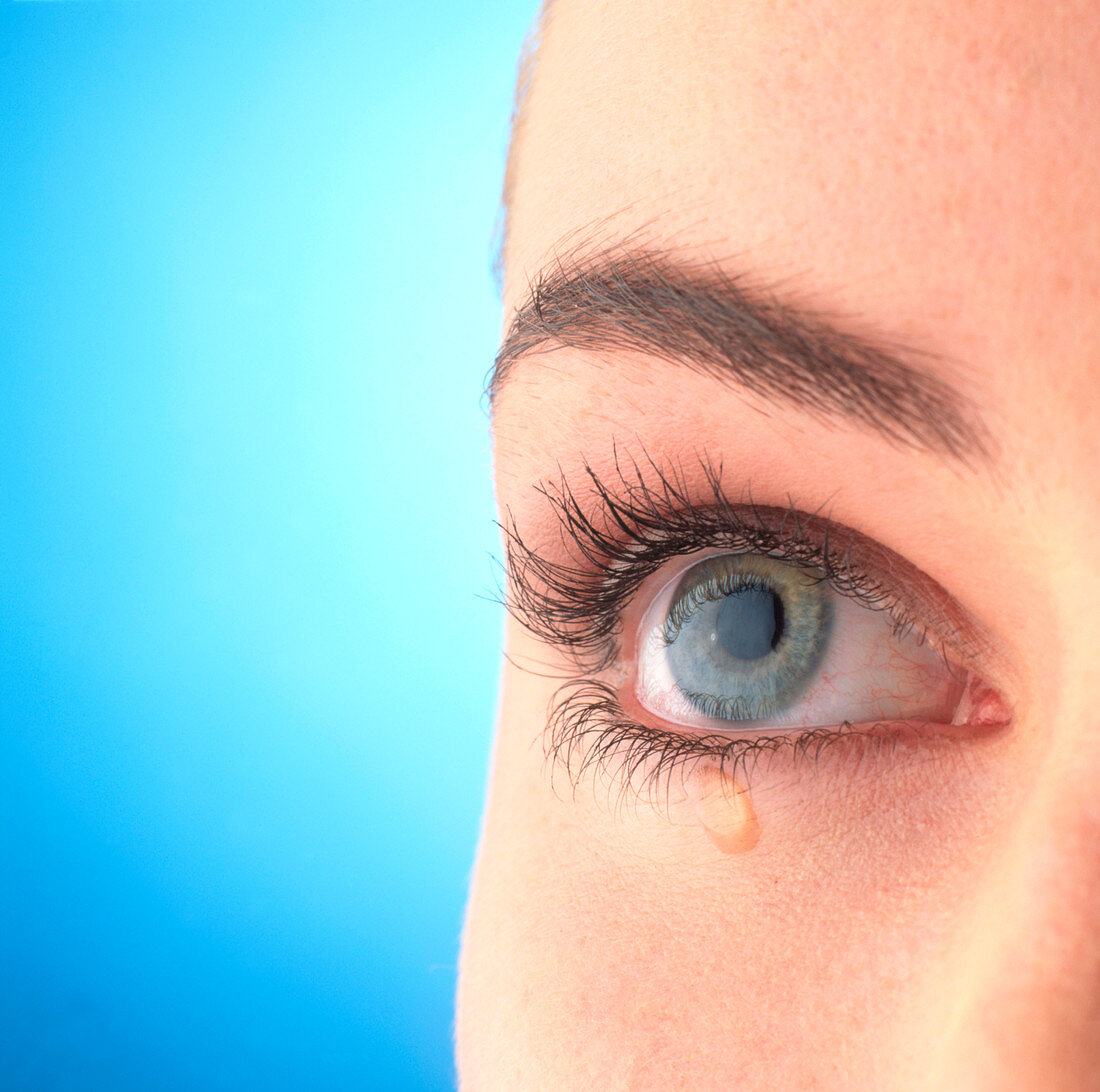Close-up of a woman's blue eye with a tear-drop