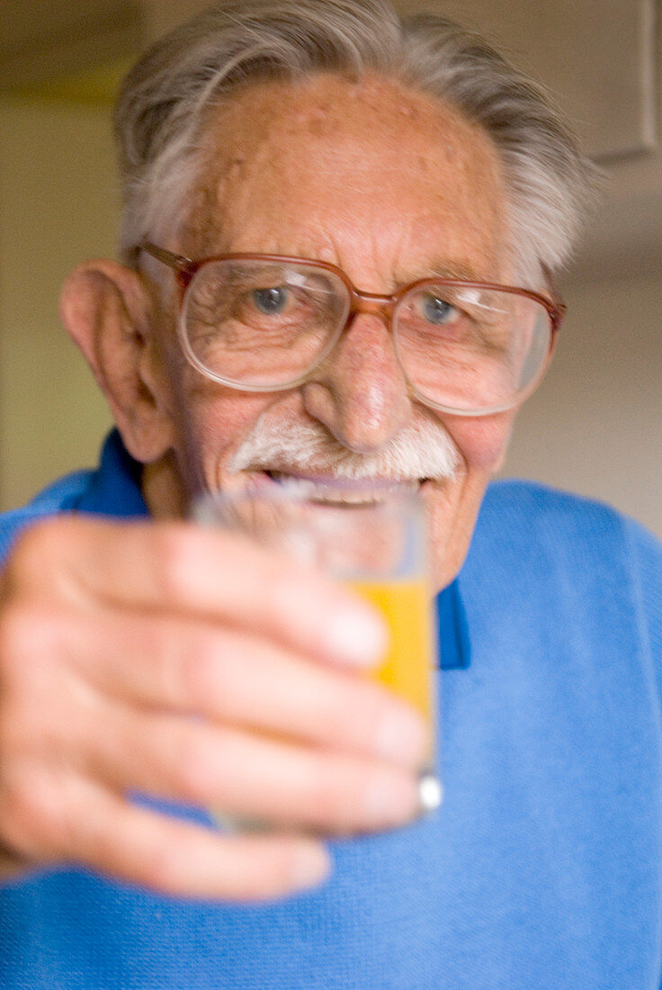 Elderly man holding a glass of juice
