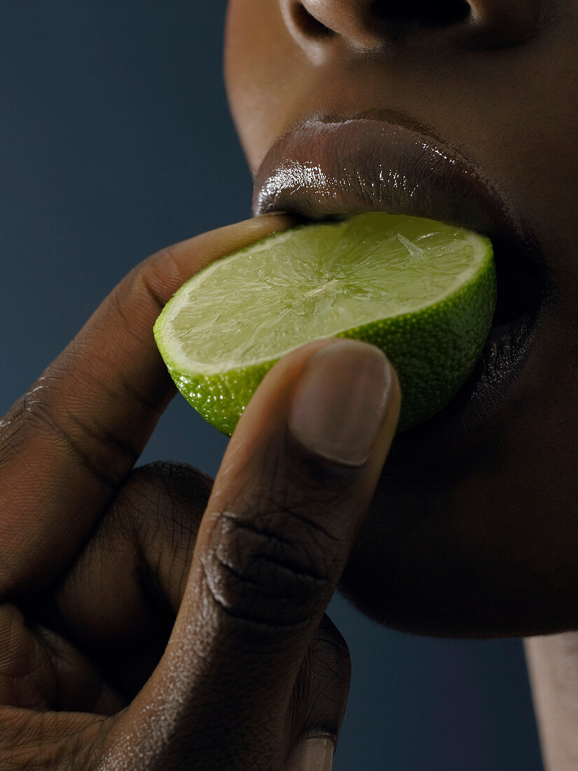 Woman sucking on a lime