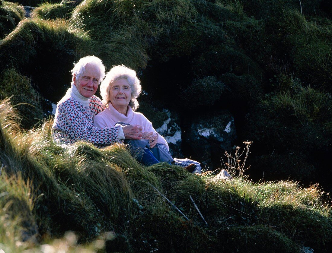 Elderly couple on a grassy slope in countryside