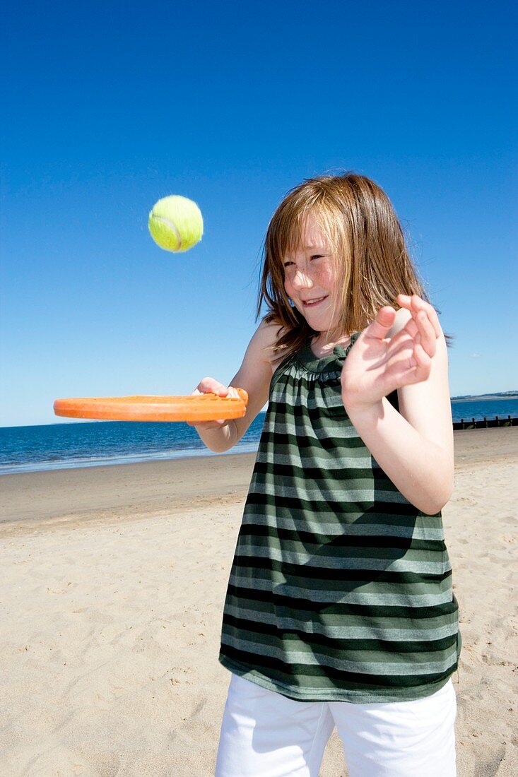 Girl playing with a bat and ball