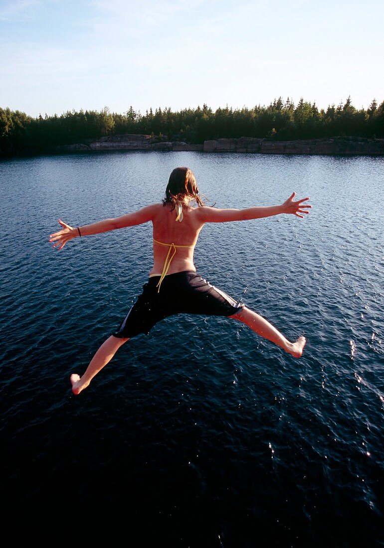 Girl jumping into a lake