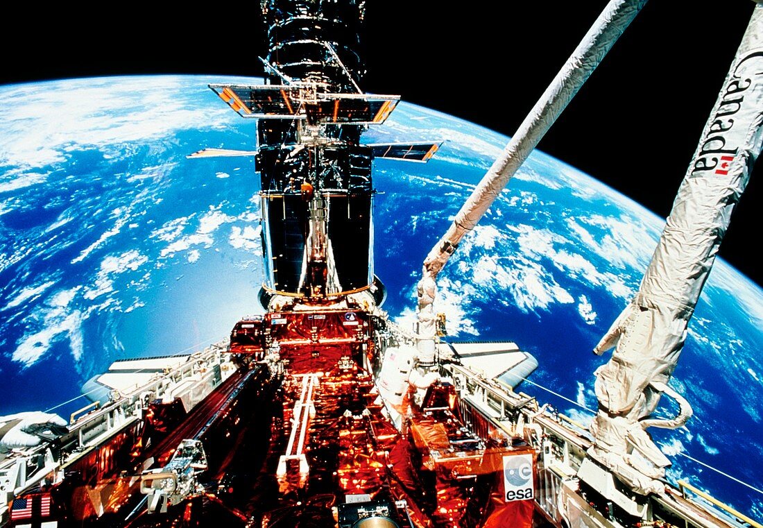 HST seen during solar panel deployment,STS-61