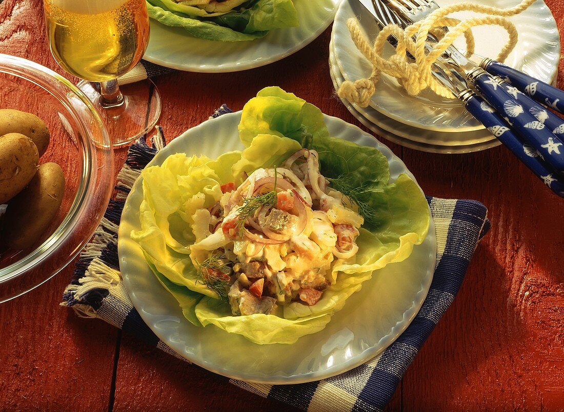 Matje herring salad served on salad leaves with boiled potatoes