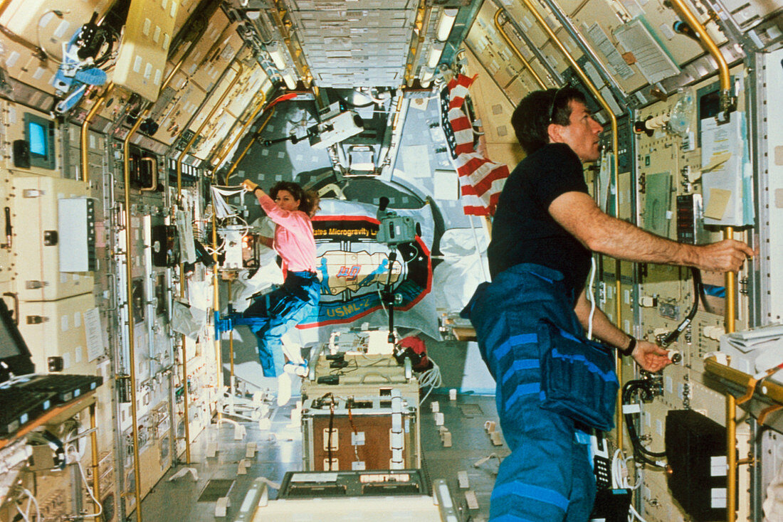 Astronauts working in a laboratory on the shuttle