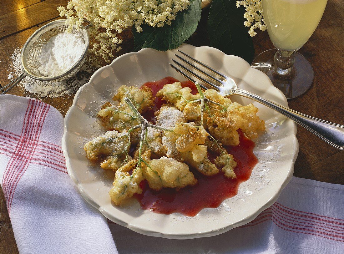 Ausgebackene Holunderblüten mit Fruchtsauce auf Teller