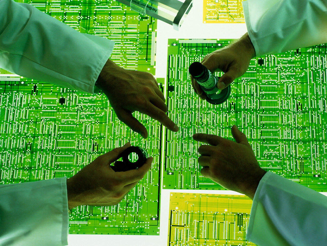Technicians examine a circuit board design