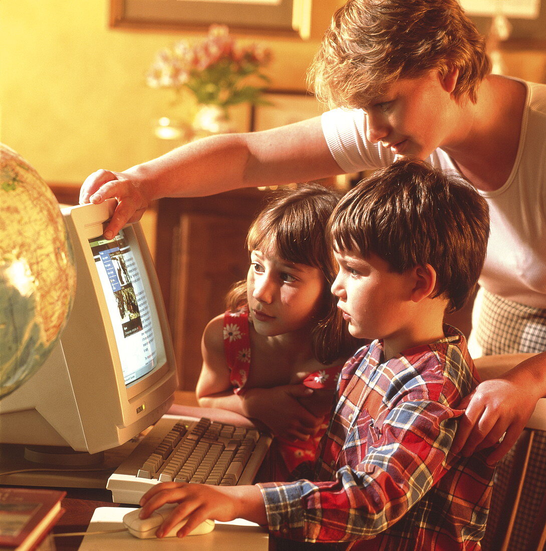 Mother helping her children to use a home computer