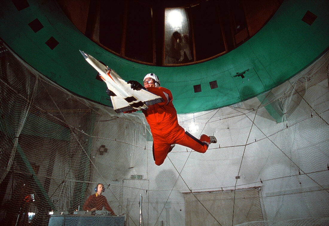 Man with aircraft model in a vertical wind tunnel