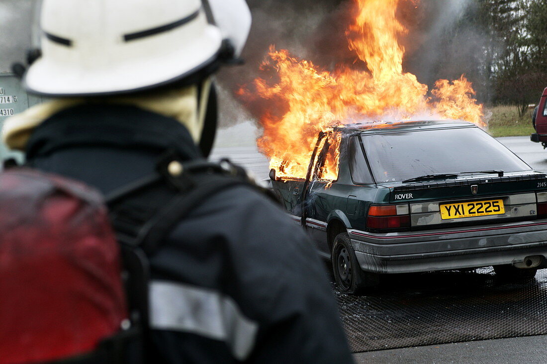 Firefighter approaching a burning car