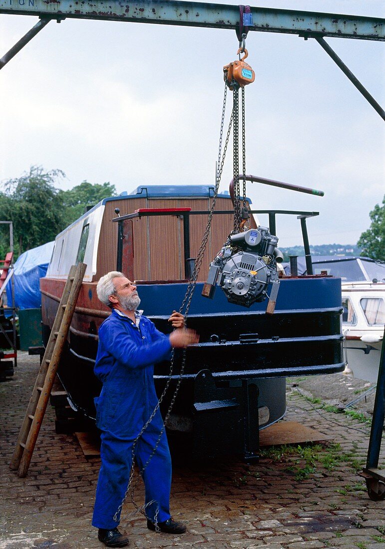 Engineer using block & tackle to lift boat engine