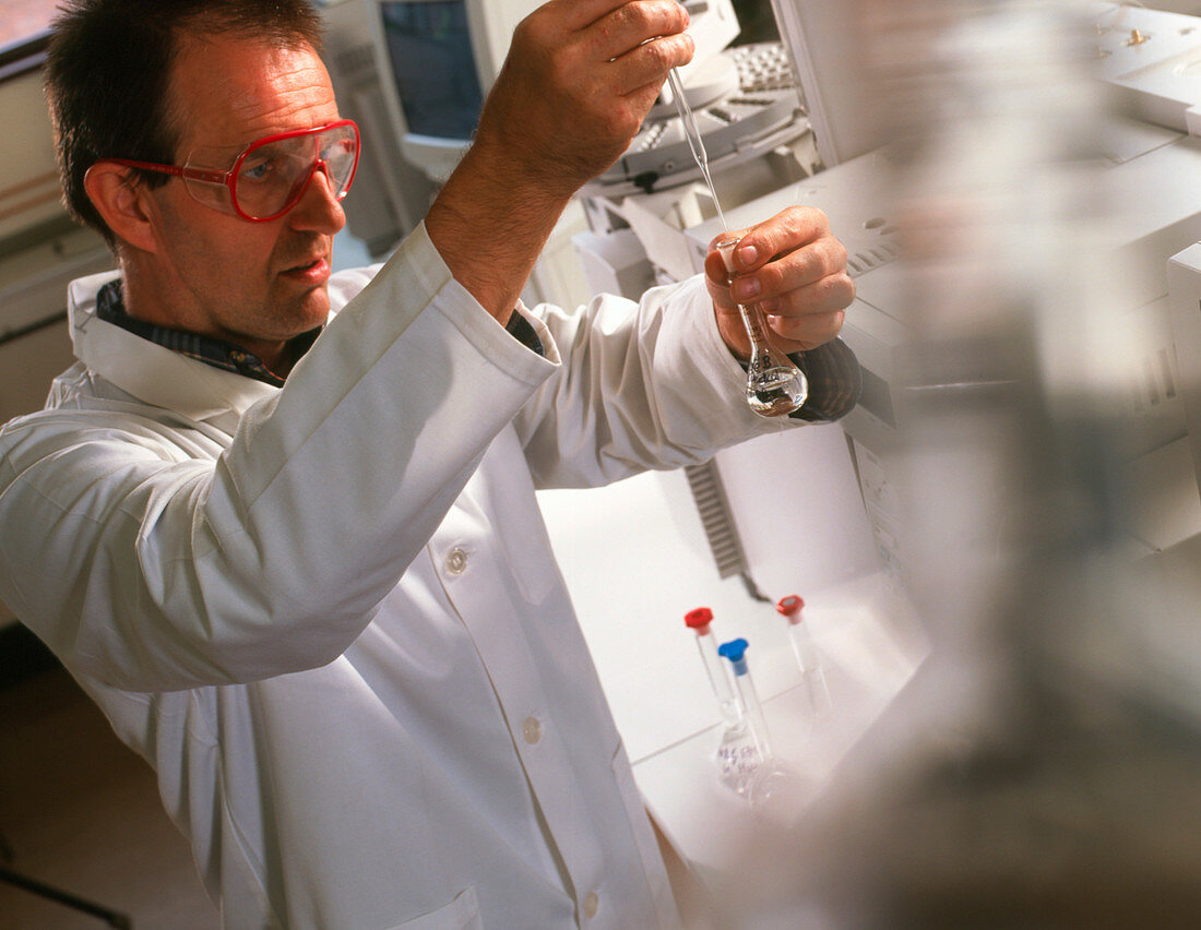 Male chemist in lab pipettes liquid into a flask