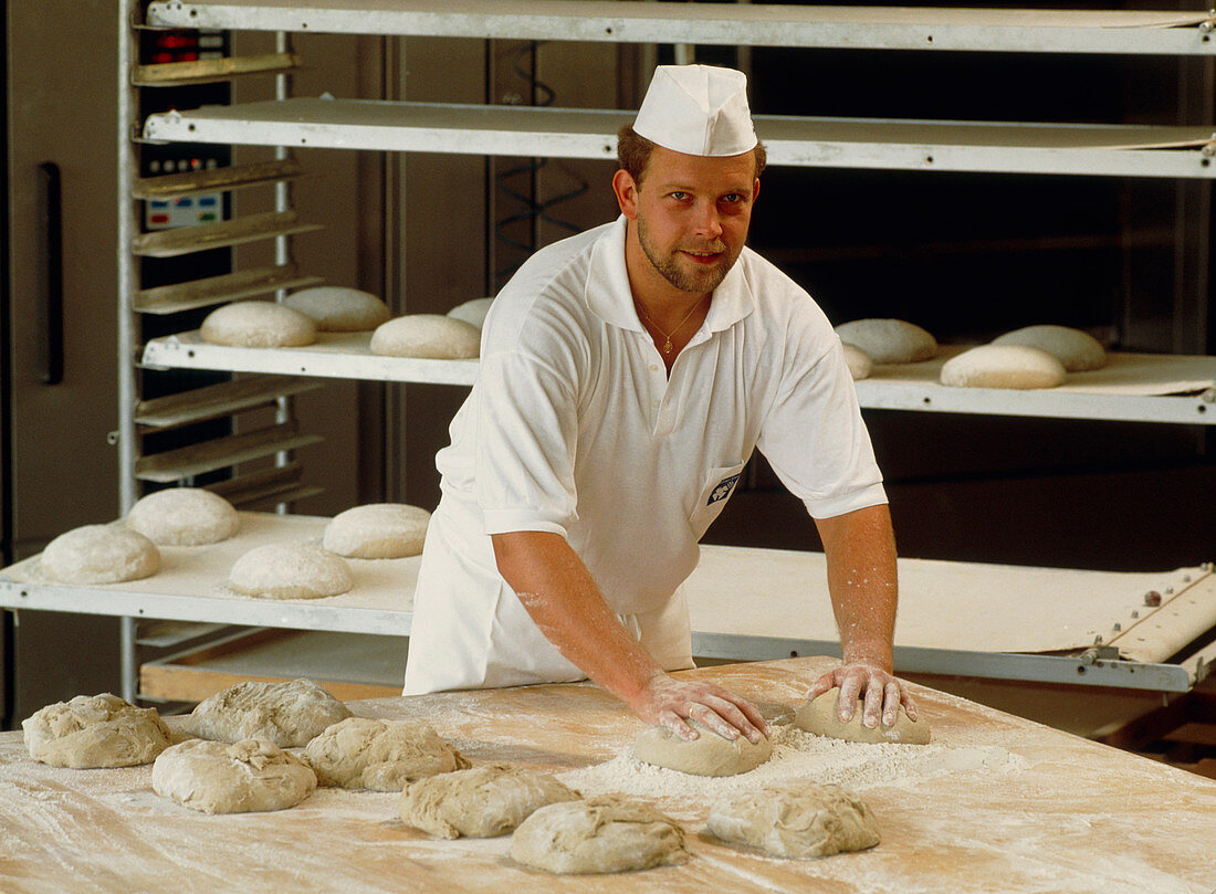 Baker kneading dough for making loaves of bread