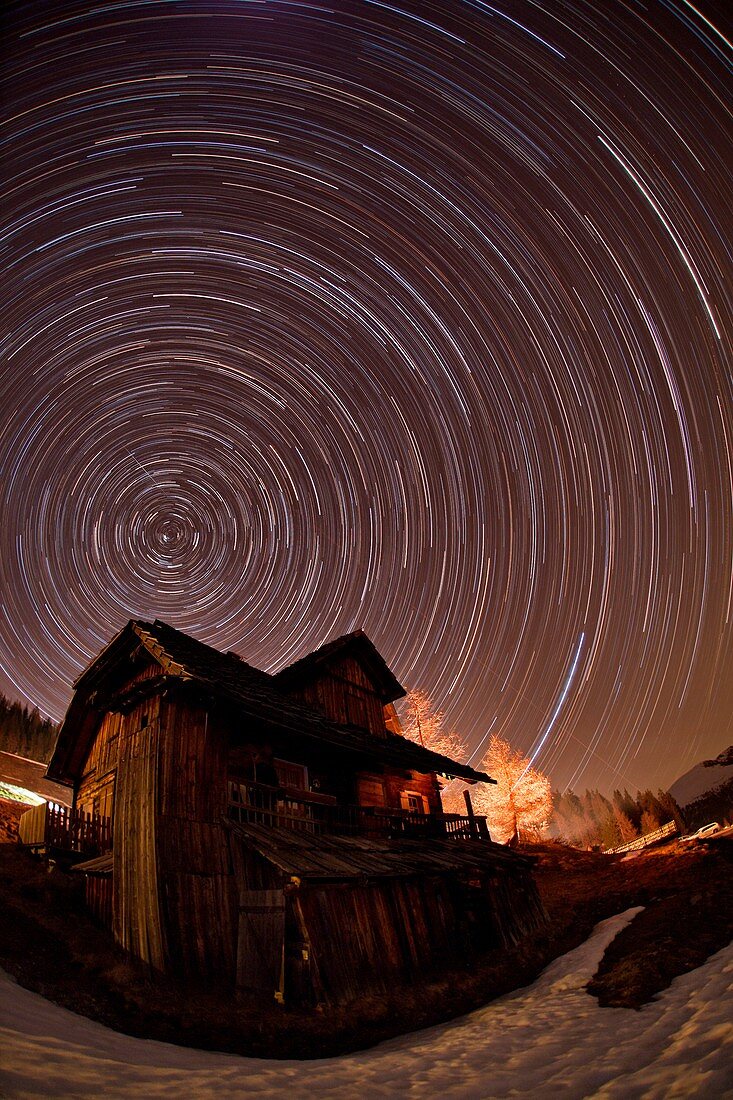 Star trails over an Alpine cottage