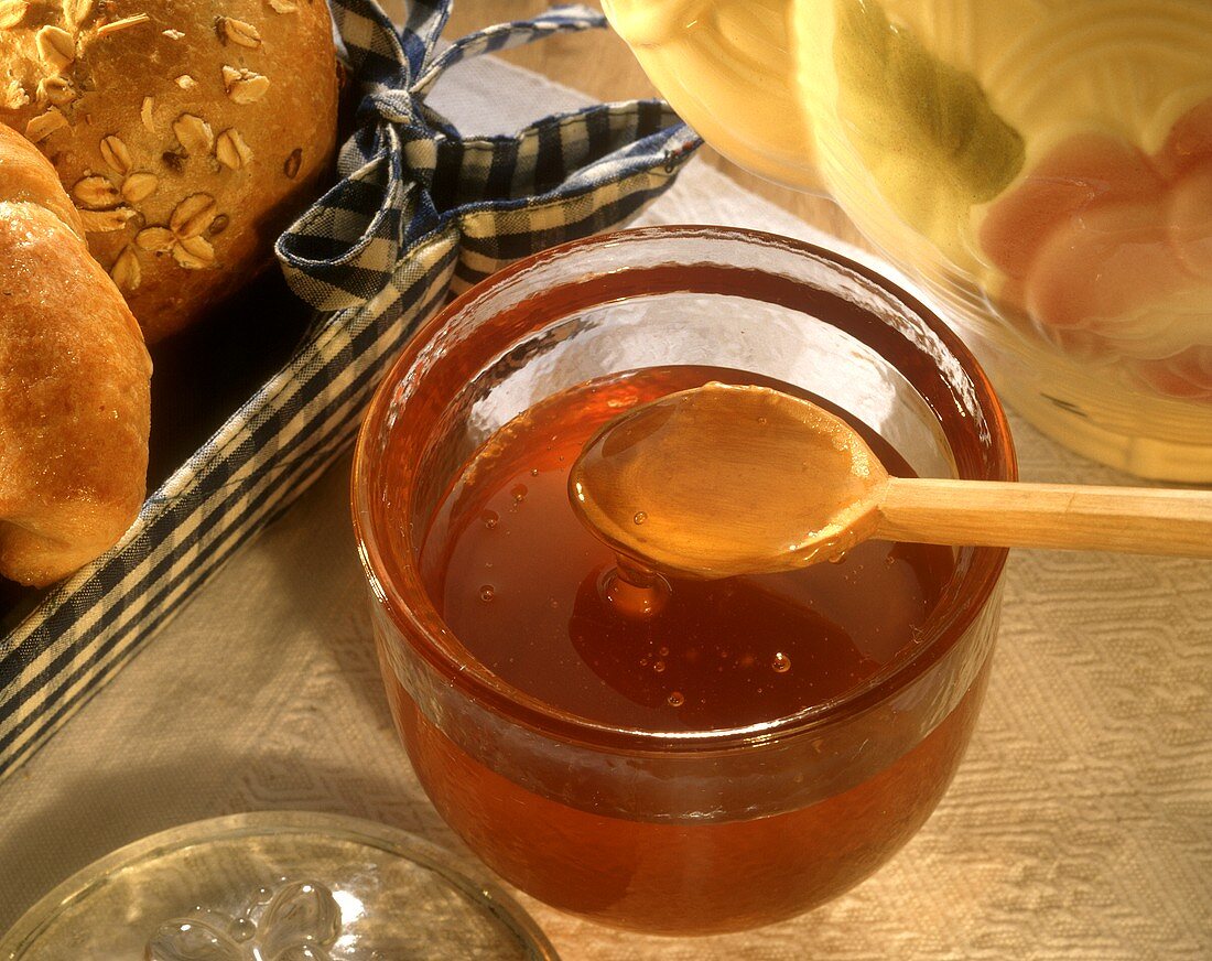 A Wooden Spoon Scooping Honey From a Glass Bowl