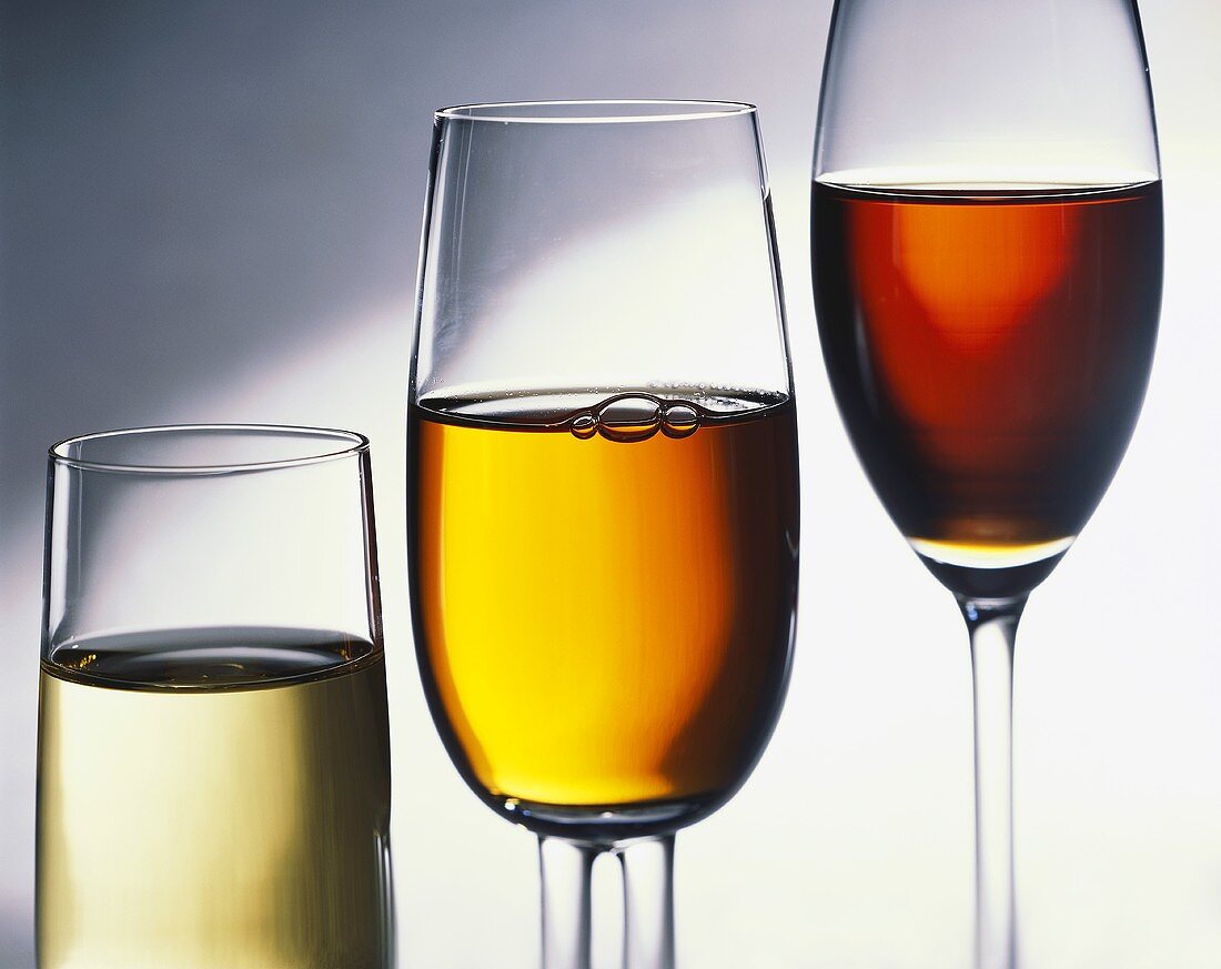 Drei verschieden hohe Gläser mit Weißwein, Rose und Rotwein